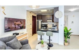 ein Wohnzimmer mit Sofa und eine Küche in der Unterkunft Al Reef Modern Escape -Sleek, Sunny & Serene in Abu Dhabi