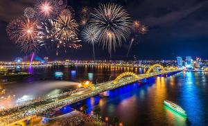 a fireworks display over a river with a bridge at Moonlight Hotel & Suites - Highfloor view of the city center and Dragon Bridge in Danang