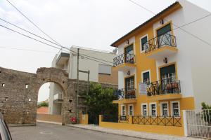 een geel en wit gebouw met een stenen muur bij Vina's Place in Nazaré