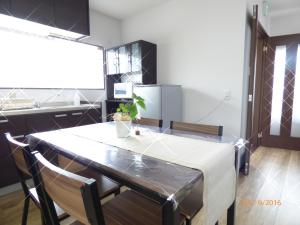 a kitchen with a table and chairs and a refrigerator at SAIZEN Matsumuro stay in Kyoto