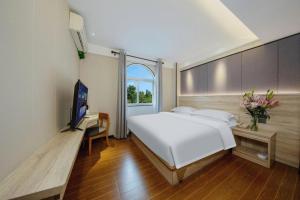 a bedroom with a white bed and a television at Wenxing Hotel Guangzhou Huajing Xincheng Branch in Guangzhou +197 photos