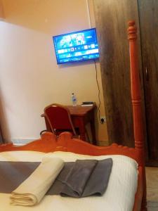 a bedroom with a bed with a desk and a tv at Villa Serene Hotel Kitale in Kitale