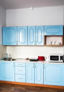 a blue kitchen with white cabinets and a microwave at Apartments na Lenina in Nevel'