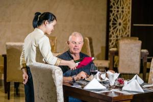 Une femme qui donne à un homme une carte rouge à une table dans l'établissement Muong Thanh Grand Ha Tinh Hotel, à Kỳ Anh