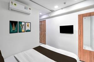 Cette chambre comprend un lit et une télévision. dans l'établissement Super Hotel O Sneh Rashmi Botanical Garden Surat Formerly Stadium Plaza, à Bhatha 24 autres photos