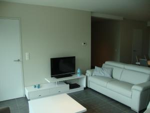 a living room with a couch and a flat screen tv at Karthuizer Zeezicht I in Nieuwpoort