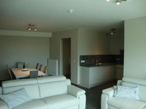 a living room with a white couch and a kitchen at Karthuizer Zeezicht I in Nieuwpoort