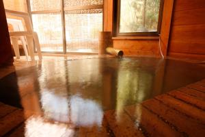 a room with a wooden floor and a window at Shimizu Ryokan in Yufu