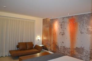 - un salon avec une chaise et un mur orné de peinture rouillée dans l'établissement Hotel Marfil, à Sant Antoni de Portmany