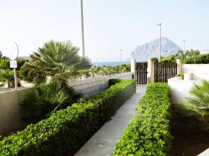 a walkway with bushes and a fence and palm trees at Case Vacanza Tra I Due Monti in Valderice