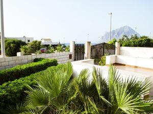 a garden with palm trees and a white fence at Case Vacanza Tra I Due Monti in Valderice
