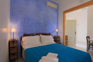 una camera blu con un letto con cuscini bianchi di Borgo Marino Plemmirio a Siracusa