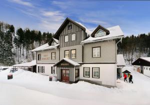 a large house with people standing in the snow at Hotel Hradec in Špindlerův Mlýn