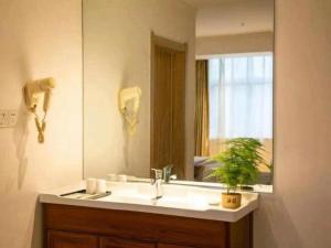 une salle de bain avec un lavabo et un miroir dans l'établissement GreenTree Inn Henan Shangqiu Yongcheng Ouya Road Business Hotel, à Houling 95 autres photos