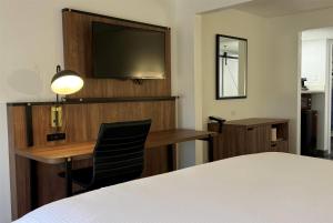 a hotel room with a bed and a desk and a television at Wingate by Wyndham Airport - Rockville Road in Indianapolis