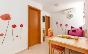 a dining room with a table and flowers on the wall at Apartments Mali Raj in Vranjic