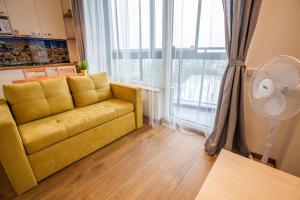 ein Wohnzimmer mit einem gelben Sofa und einem großen Fenster in der Unterkunft Sky Studio near the Vilnius Center in Vilnius