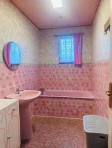 Baño de color rosa con lavabo y bañera en Clos des hortensias, en Fatouville-Grestain