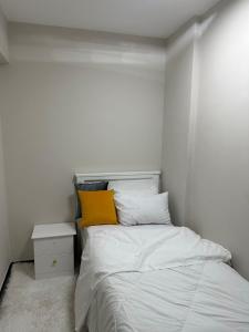 a white bedroom with a bed with a yellow pillow at Marlynlo Stays and Realty in Nairobi