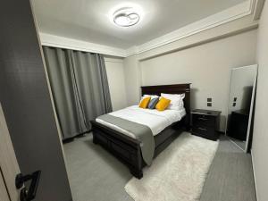 a bedroom with a bed with yellow pillows and a mirror at Marlynlo Stays and Realty in Nairobi