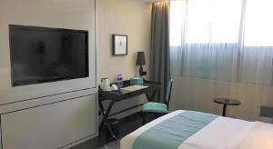 une chambre d'hôtel avec un lit et un bureau avec une télévision dans l'établissement Xana Hotelle XiAn Gig Wild Goose Pagoda Branch, à Xi'an