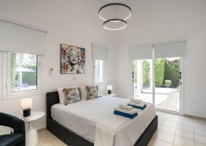 a bedroom with a large white bed and a chair at Villa Adela Coral-Bay 3B, Private Pool, Seaside in Peyia