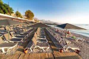 a row of lounge chairs and umbrellas on a beach at Golden Lotus Hotel in Kemer