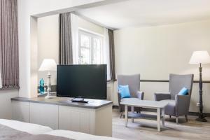 a hotel room with a television and chairs at Hotel Klein Amsterdam in Friedrichstadt
