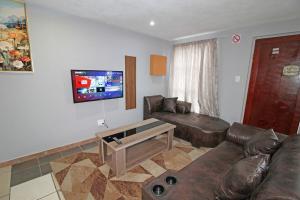 ジャーミストンにあるComfortable 2 Bedroom Flat in Germiston with WI-FIのリビングルーム(革張りのソファ、テレビ付)