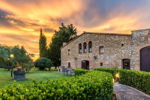 an old stone building with a sunset in the background at Hotel Mas Rabiol -Emporda-Only Adults-Eco Hotel in Peratallada