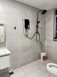 a shower in a bathroom with a toilet at Lily Homestay Villa in Kampung Sungai Baharu