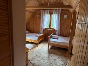 a room with two beds in a wooden house at Leśna Chata Arciechów in Arciechow