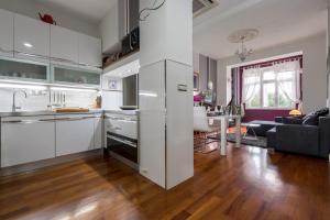 a kitchen with white cabinets and a living room at House DelMarco in Split