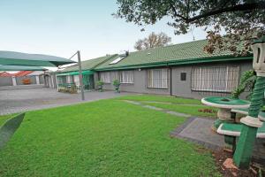 ジャーミストンにあるComfortable 2 Bedroom Flat in Germiston with WI-FIの庭に緑のベンチがある建物