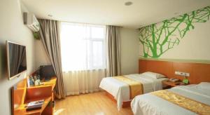 a hotel room with two beds and a television at Vatica Tianjin Jinghai Bus Station Home World Plaza Hotel in Tianjin