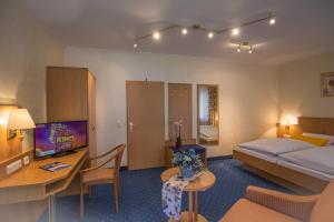 a hotel room with a bed and a desk and a television at Gasthof Rodachtal mit Gästehaus Katharina in Schwarzenbach am Wald