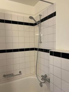 a shower in a bathroom with black and white tiles at Beautiful and bright studio flat right in front of Zurich lake in Zürich