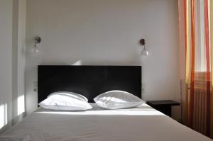 dwie poduszki na łóżku z czarnym zagłówkiem w obiekcie Maison du Cassoulet w mieście Castelnaudary