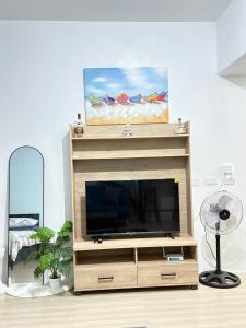 ein Wohnzimmer mit einem TV auf einem hölzernen Entertainment-Center in der Unterkunft 1BR Studio with WiFi and Pool Access in Mactan Island