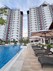 ein Pool mit Stühlen und Sonnenschirmen neben zwei hohen Gebäuden in der Unterkunft 1BR Studio with WiFi and Pool Access in Mactan Island
