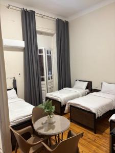 Cette chambre comprend 3 lits, une table et des chaises. dans l'établissement New Havana Hotel, au Caire