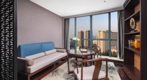 un salon avec un canapé, une table et une fenêtre dans l'établissement Yiwu Orange Boutique Hotel, à Yiwu
