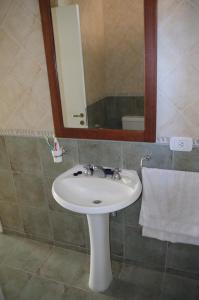 y baño con lavabo blanco y espejo. en Corvina de Pinamar en Pinamar