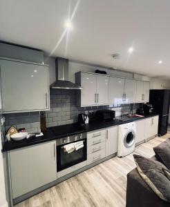 a kitchen with white cabinets and a washer and dryer at One bed flat in Sunny Southend! in Southend