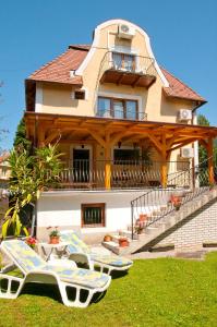 a house with two lounge chairs in front of it at Apartments Yowan in Hévíz