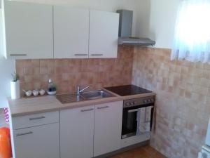 a kitchen with white cabinets and a sink and an oven at Olive House in Medulin