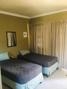 a bedroom with two beds and a window at The Hope Apartments in Nelspruit