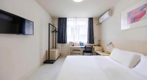 a hotel room with a large white bed and a desk at Jinjiang Inn Beijing Conference Center Bird Nest in Beijing