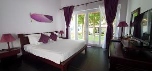 a bedroom with a bed and a tv and a window at Terrace Phú Quốc in Phu Quoc