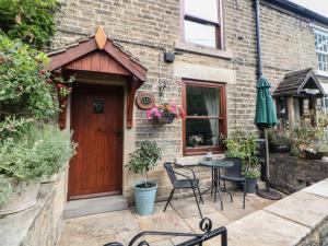 un patio avec des chaises et une table devant un bâtiment dans l'établissement Brook Cottage, à Hayfield